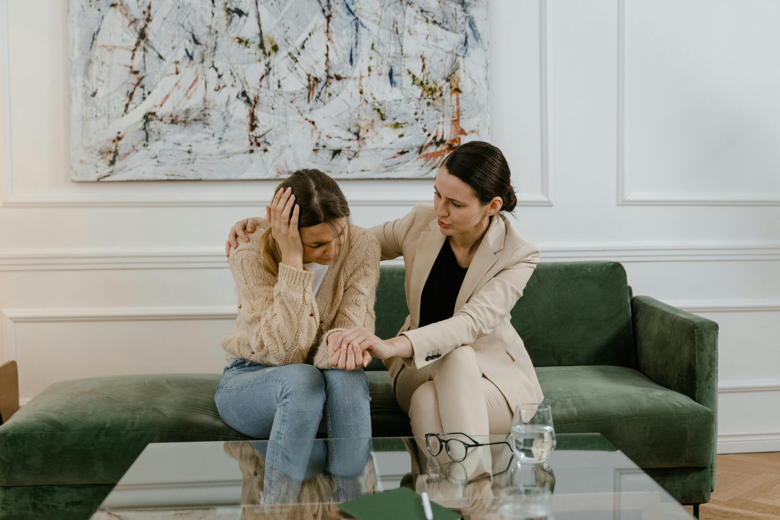 Therapist comforting a distressed young woman on a sofa