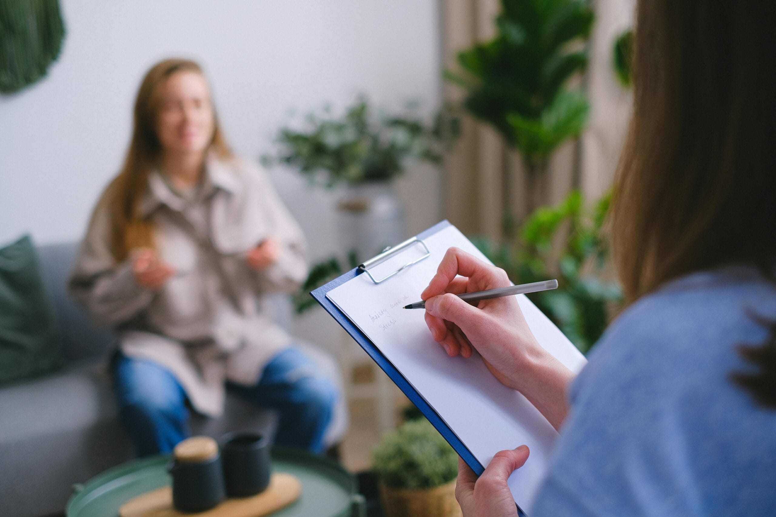 Therapist taking notes while a client talks during a session