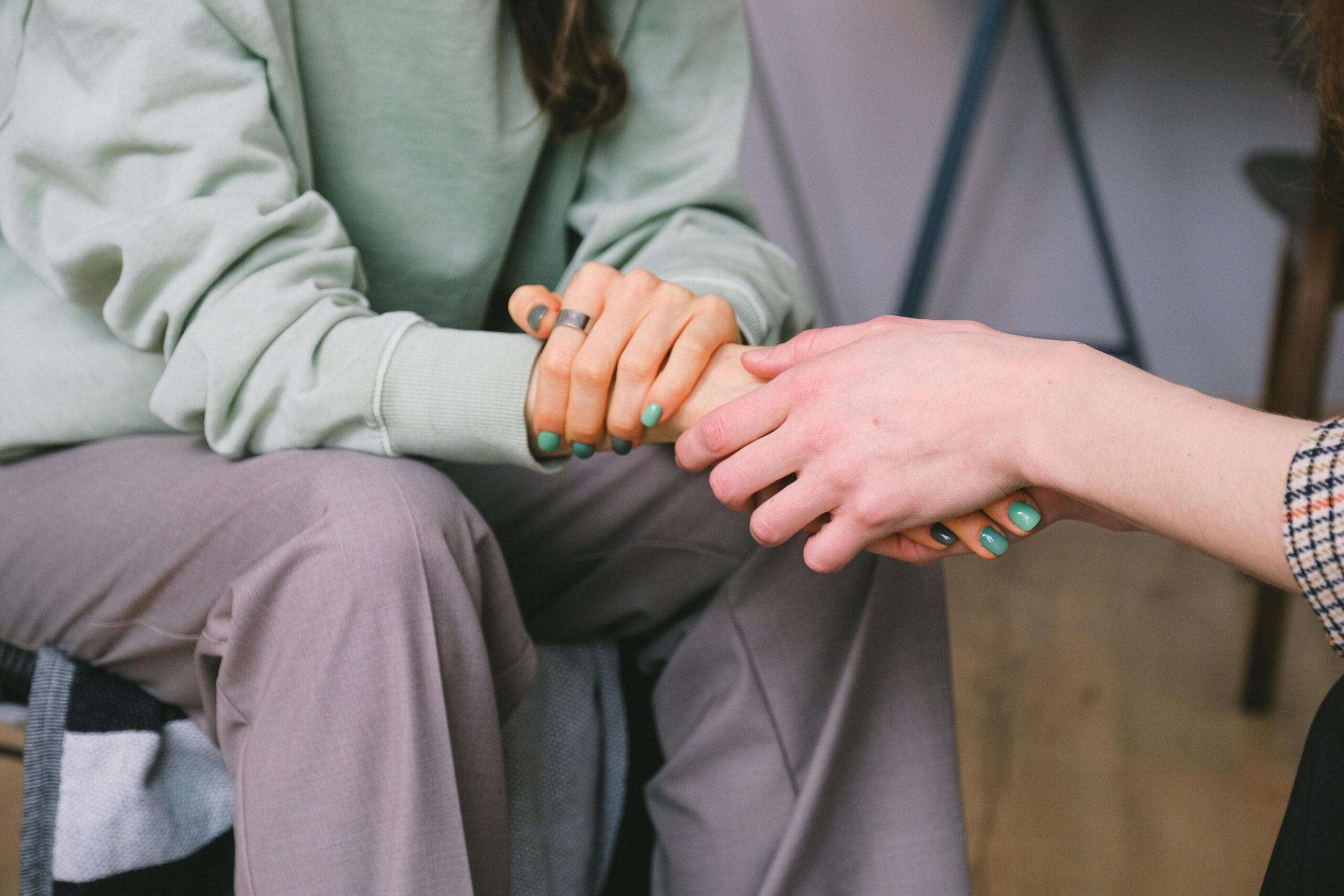 Two people holding hands in a comforting gesture